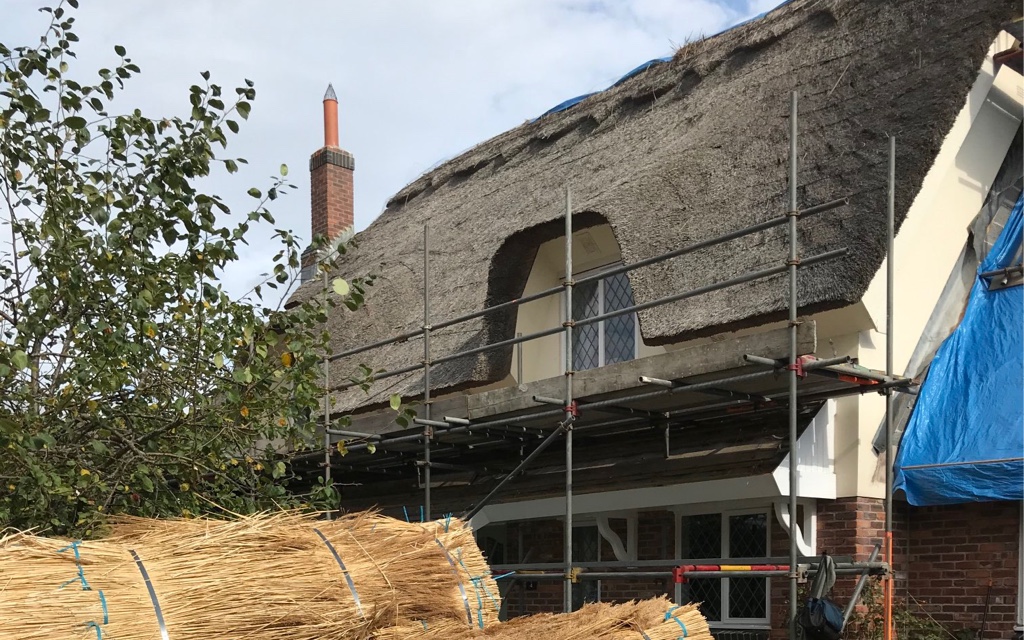 Bales of reed outside a thatched property